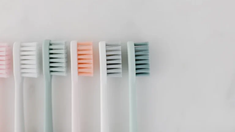 Top view of pastel-colored toothbrushes on a marble surface, ideal for dental care concepts.