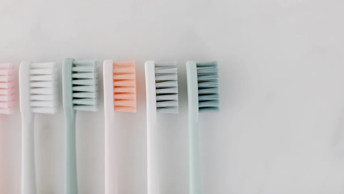Top view of pastel-colored toothbrushes on a marble surface, ideal for dental care concepts.