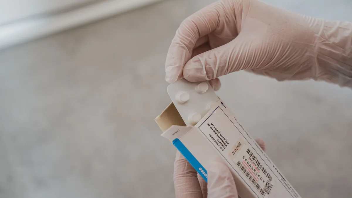 Close-up of hands in gloves handling medication blister pack, ensuring safety and hygiene in healthcare.
