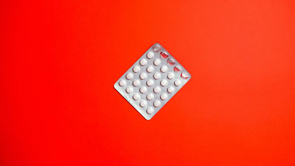 Close-up of a blister pack of pills against a solid red background symbolizing healthcare and medication.