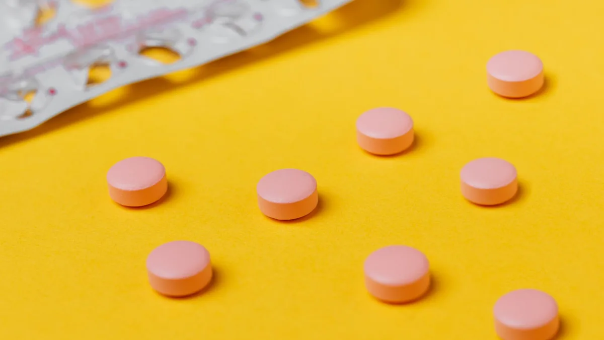 Close-up of pink pills on a vibrant yellow surface, depicting medication themes.