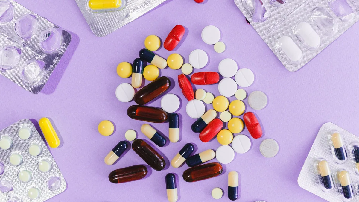 A variety of colorful pills and capsules displayed on a purple background in blister packs.