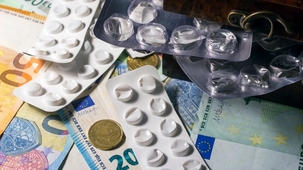 Blister packs of medication placed on Euro banknotes, illustrating healthcare expenses.