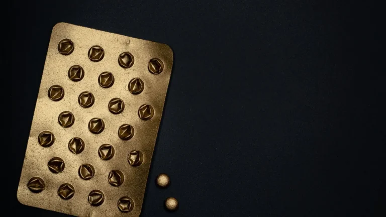 A close-up of a gold metallic blister pack on a black surface, ideal for healthcare themes.