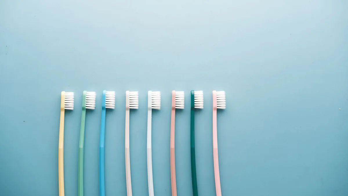 An assortment of colorful toothbrushes arranged on a vibrant blue background in a minimalist style.