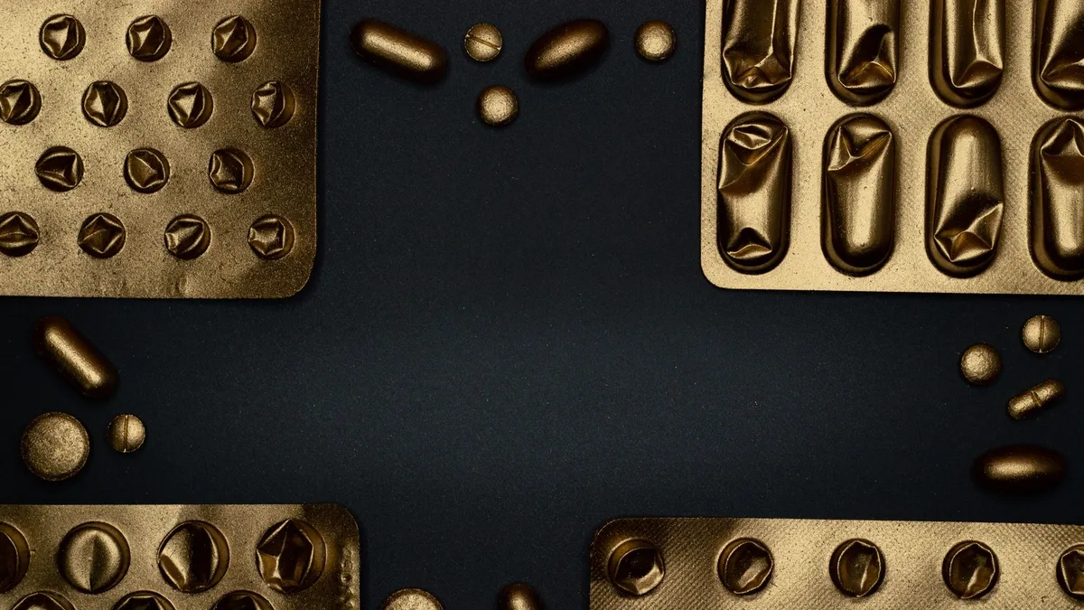 Close-up of metallic pills and blister packs on a dark surface, showcasing healthcare themes.