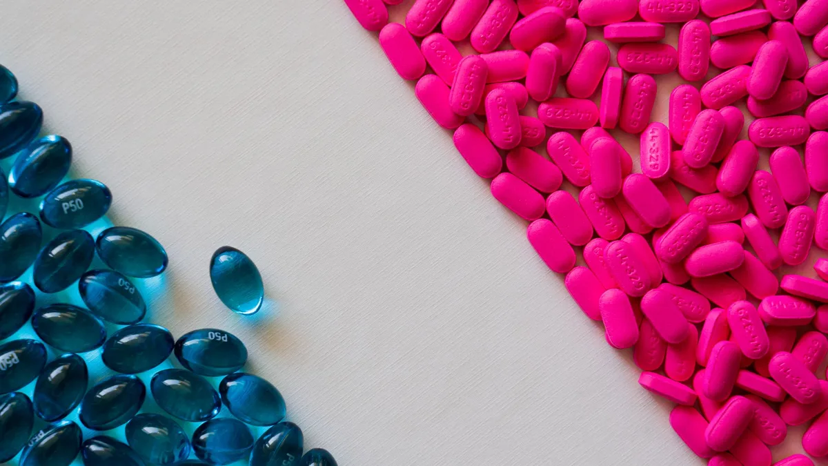 Close-up of blue gel capsules and pink tablets on a white background.