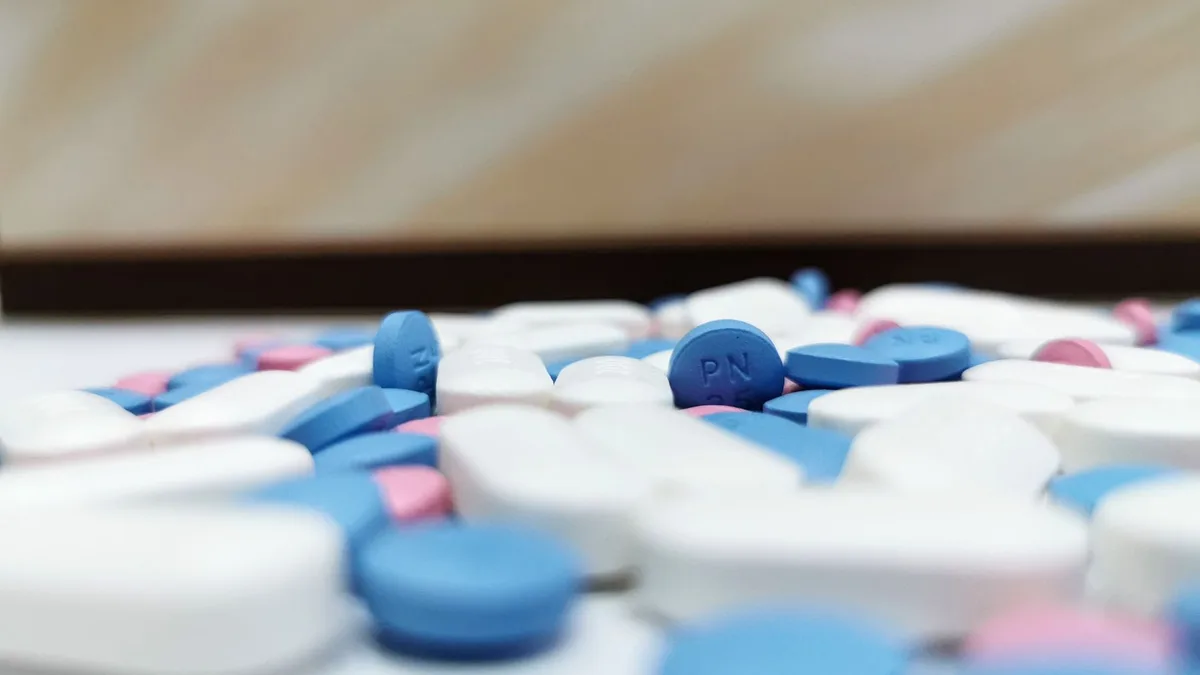 Close-up image of assorted blue and white pills scattered on a table, indoors.