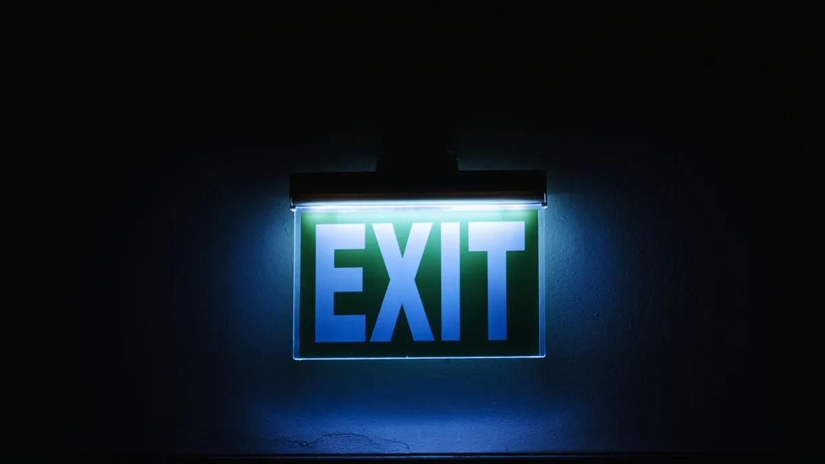 Photo of a glowing green exit sign in a dark environment, symbolizing safety and direction.