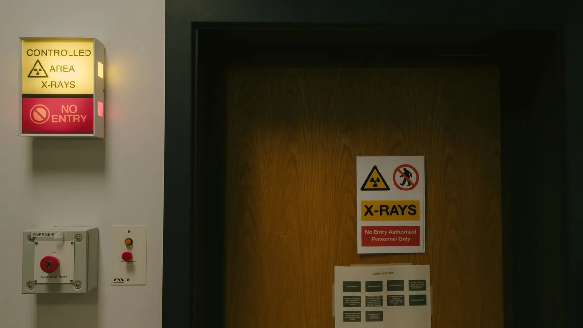 Warning signs on a wooden door indicating a controlled X-ray area with no entry restriction.