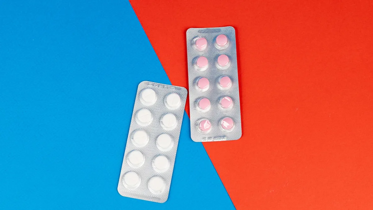 Flat lay of pill blister packs on a red and blue surface, ideal for healthcare themes.