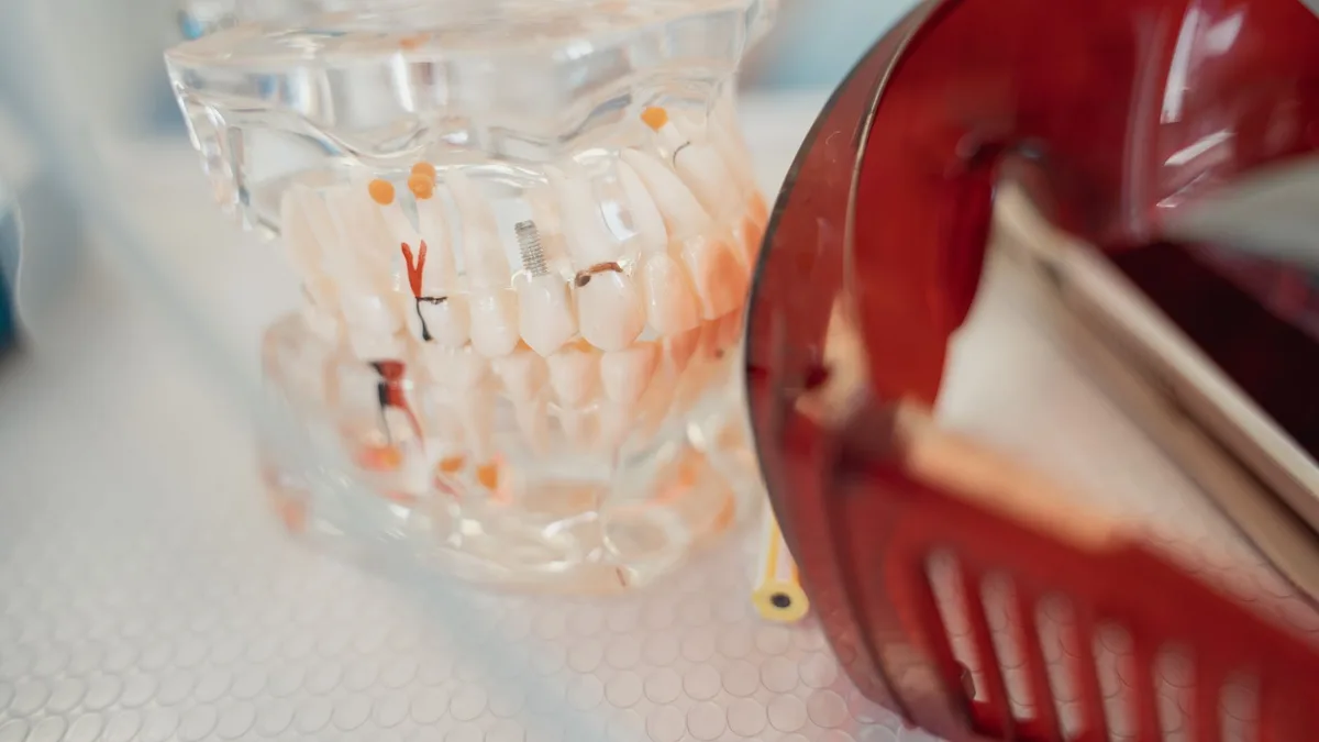 A dental model and red protective glasses on a textured surface, highlighting dental health tools.