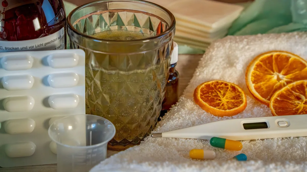 A collection of home remedies and medications for treating cold and flu symptoms, including a thermometer, pills, and herbal tea.