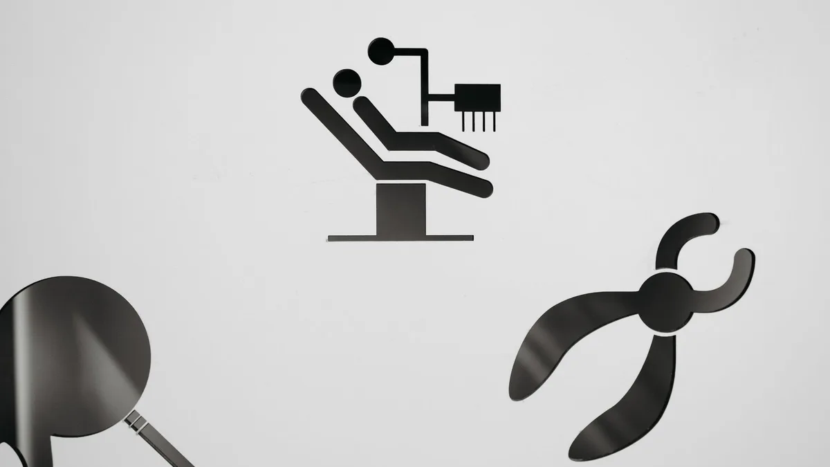 Black dental symbols on a white background, featuring a chair, mirror, and pliers.