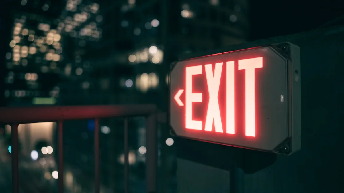 Bright red exit sign glowing against a blurred urban cityscape at night.