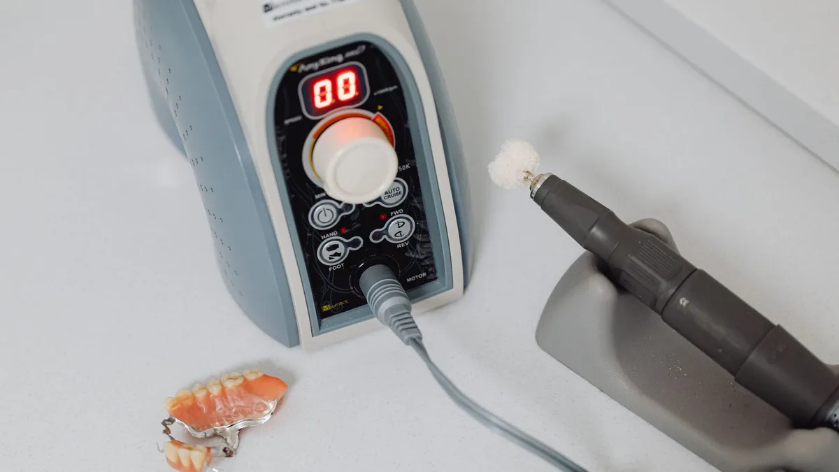 Close-up of dental machine and denture on countertop, showcasing dental technology.