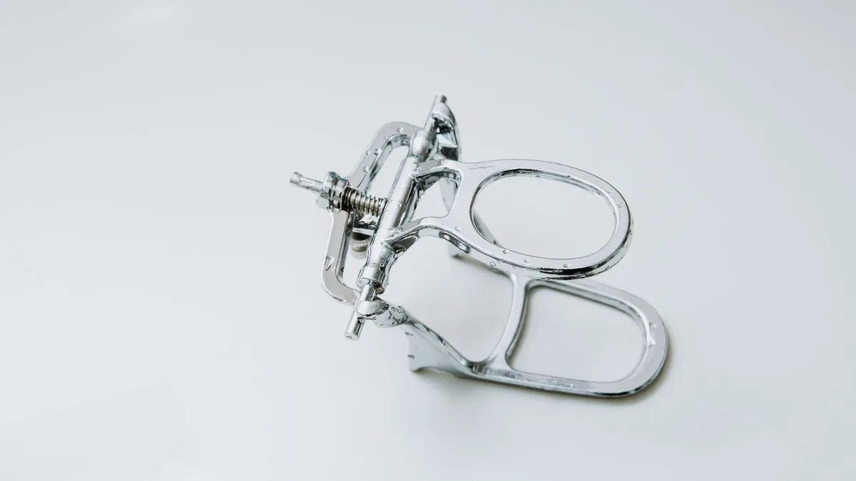 From above of metal dental occluder used for creating denture placed on white background