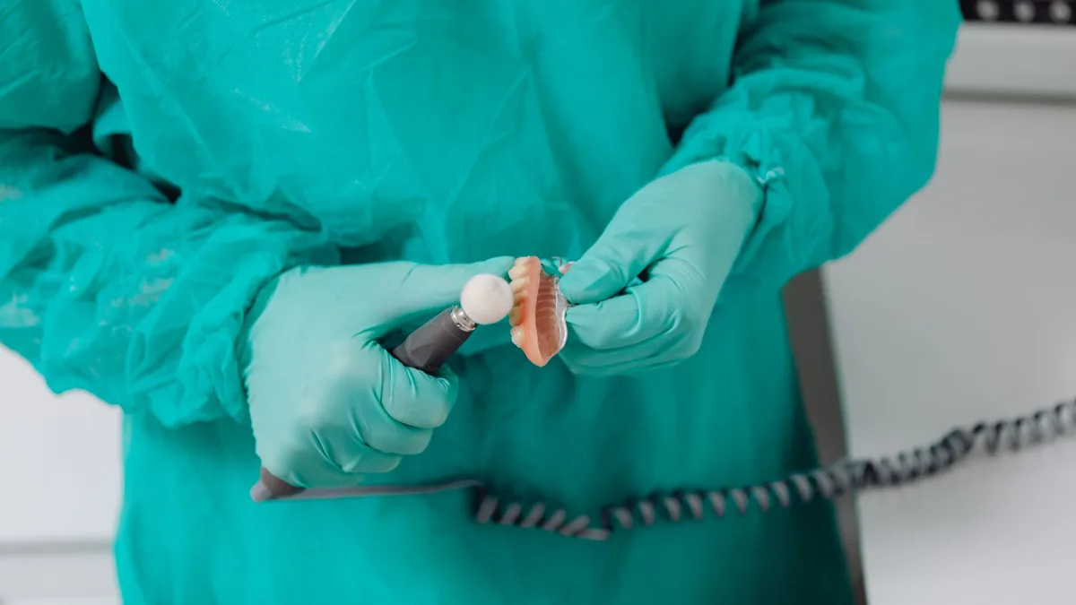 Close-up of a dental professional wearing gloves polishing dentures with care.