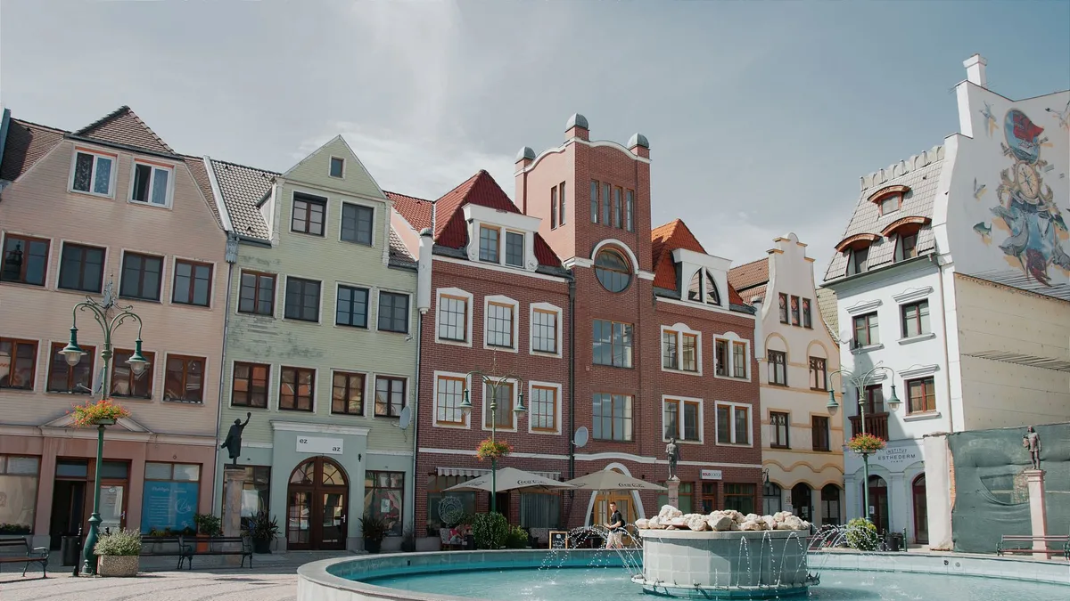 A vibrant square in Komárno featuring colorful facades and a central fountain.