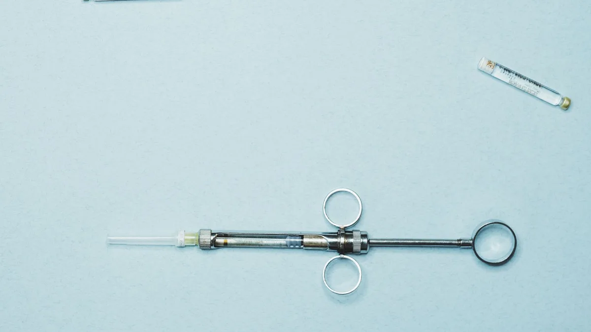 High-quality stock photo of a dental syringe and vials on a blue background. Ideal for dentistry.